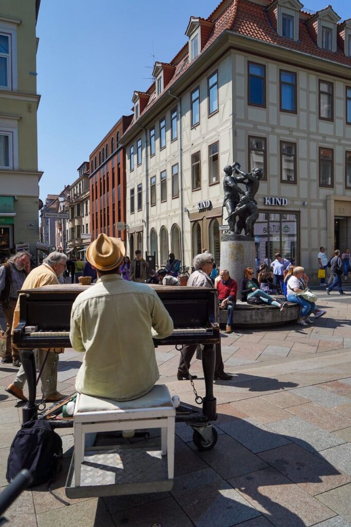 The Nabel in Göttingen with peoply walking by and a piano player in the front