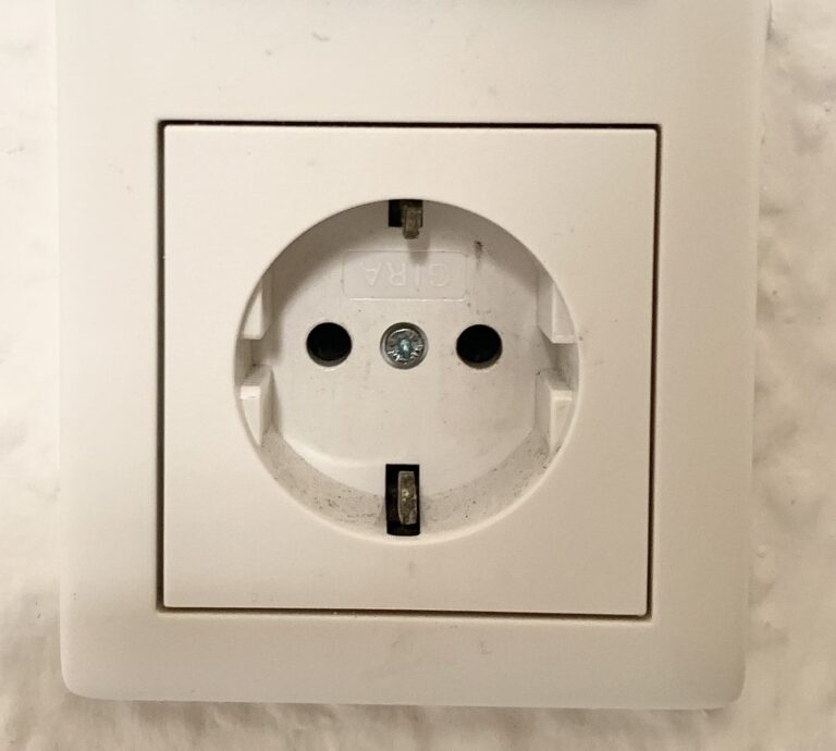 Close-up view of a Type F electrical plug socket commonly found in Germany, featuring a round recessed design with two round holes and grounding clips.