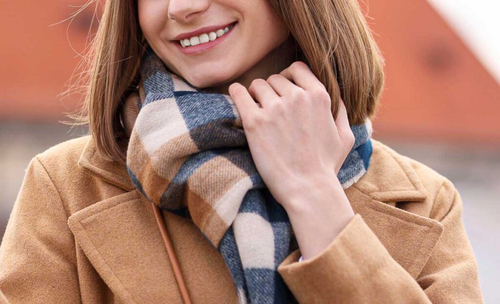 A woman wearing a scarf and a beige coat in fall in Germany